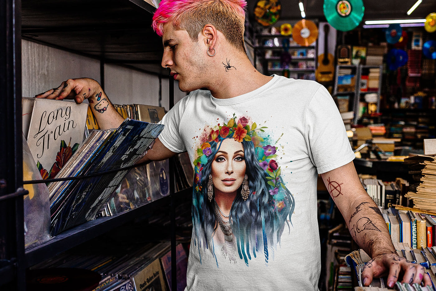 Tattooed young man at a vinyl record store, wearing Gllamazon's Cher-ry Blossom Cher T-shirt. Color: White.