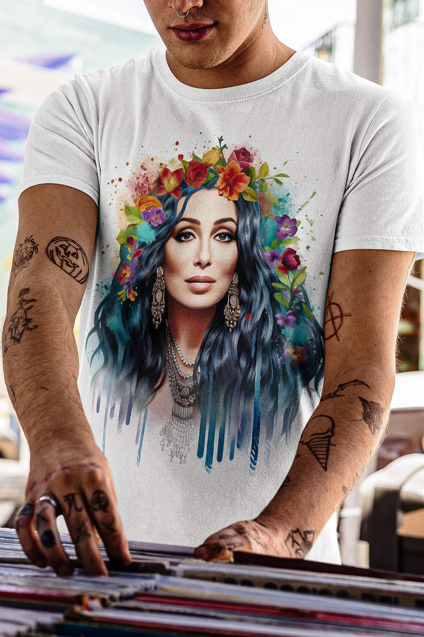 Tattooed young man at a music store wearing Gllamazon's Cher-ry Blossom Cher T-shirt. Color: White.