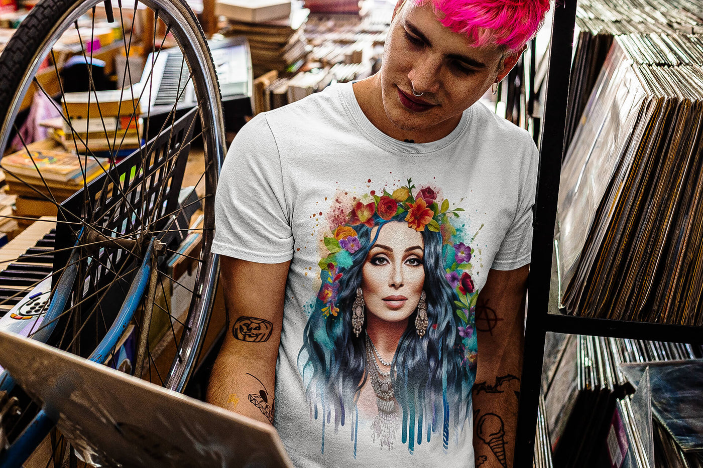 Tattooed young man at a vinyl record store, wearing Gllamazon's Cher-ry Blossom Cher T-shirt. Color: White.